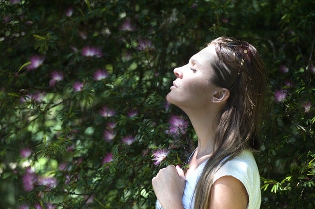 woman breathing deep standing by a plant