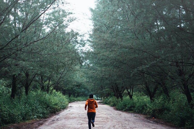 Jogger running outside in wooded area.