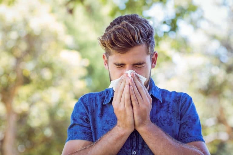 Man blowing his nose while out at the park.