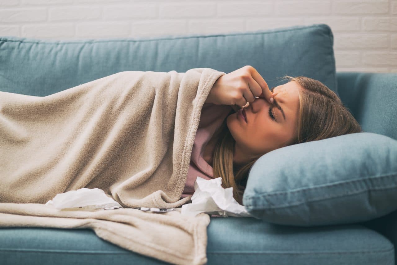 Woman with allergy symptoms lying on a couch.