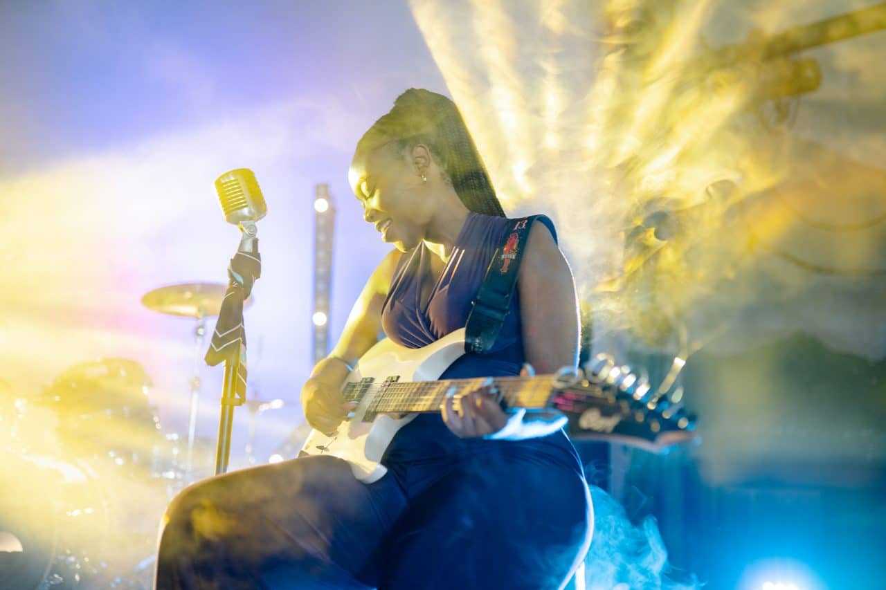 Female musician playing guitar on stage.