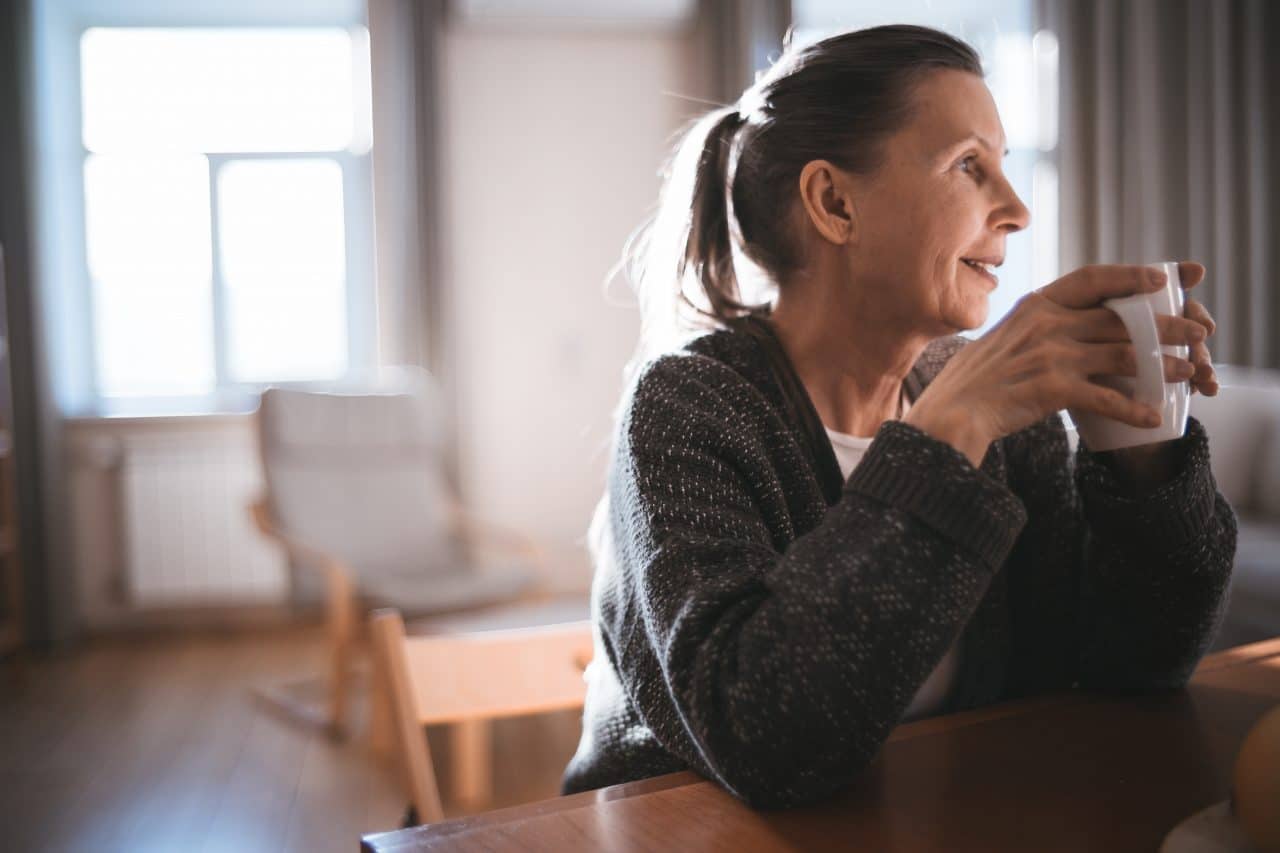 Woman drinking coffee at her kitchen table.