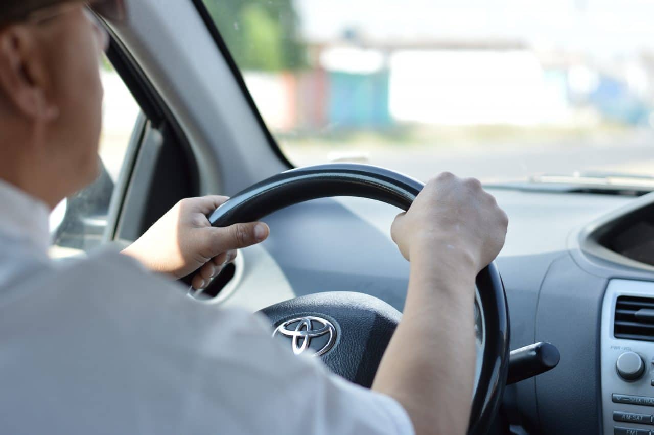Man driving with hands on steering wheel.