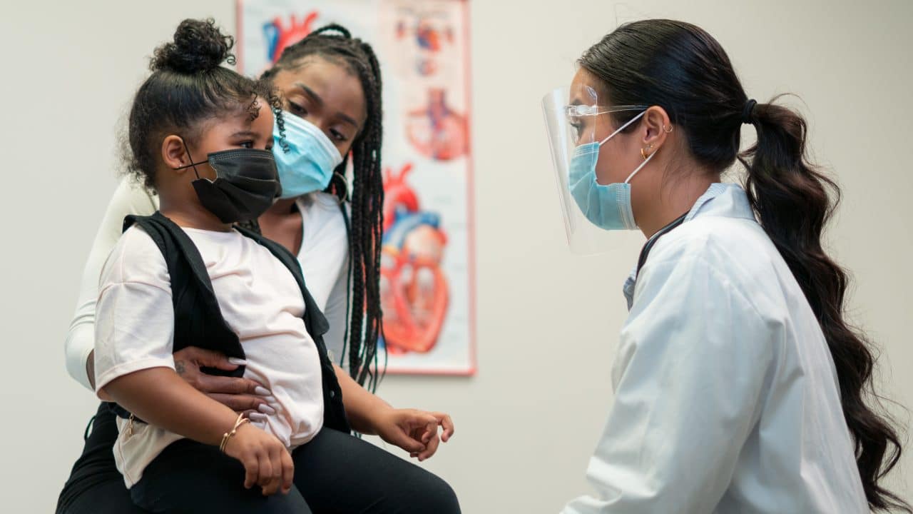 Mother and doctor speak with a pediatric doctor.