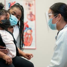 Mother and doctor speak with a pediatric doctor.