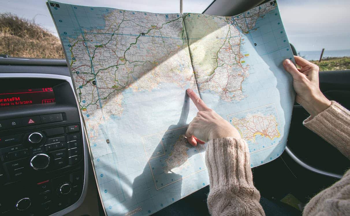 Passenger in a car points at a map on a roadtrip.