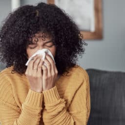 Woman with allergies blowing her nose.