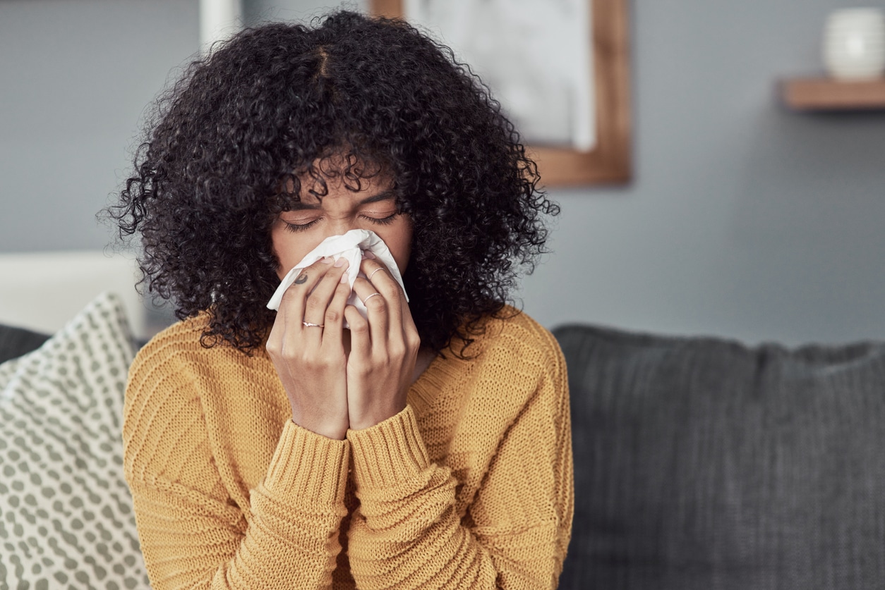 Woman with allergies blowing her nose.