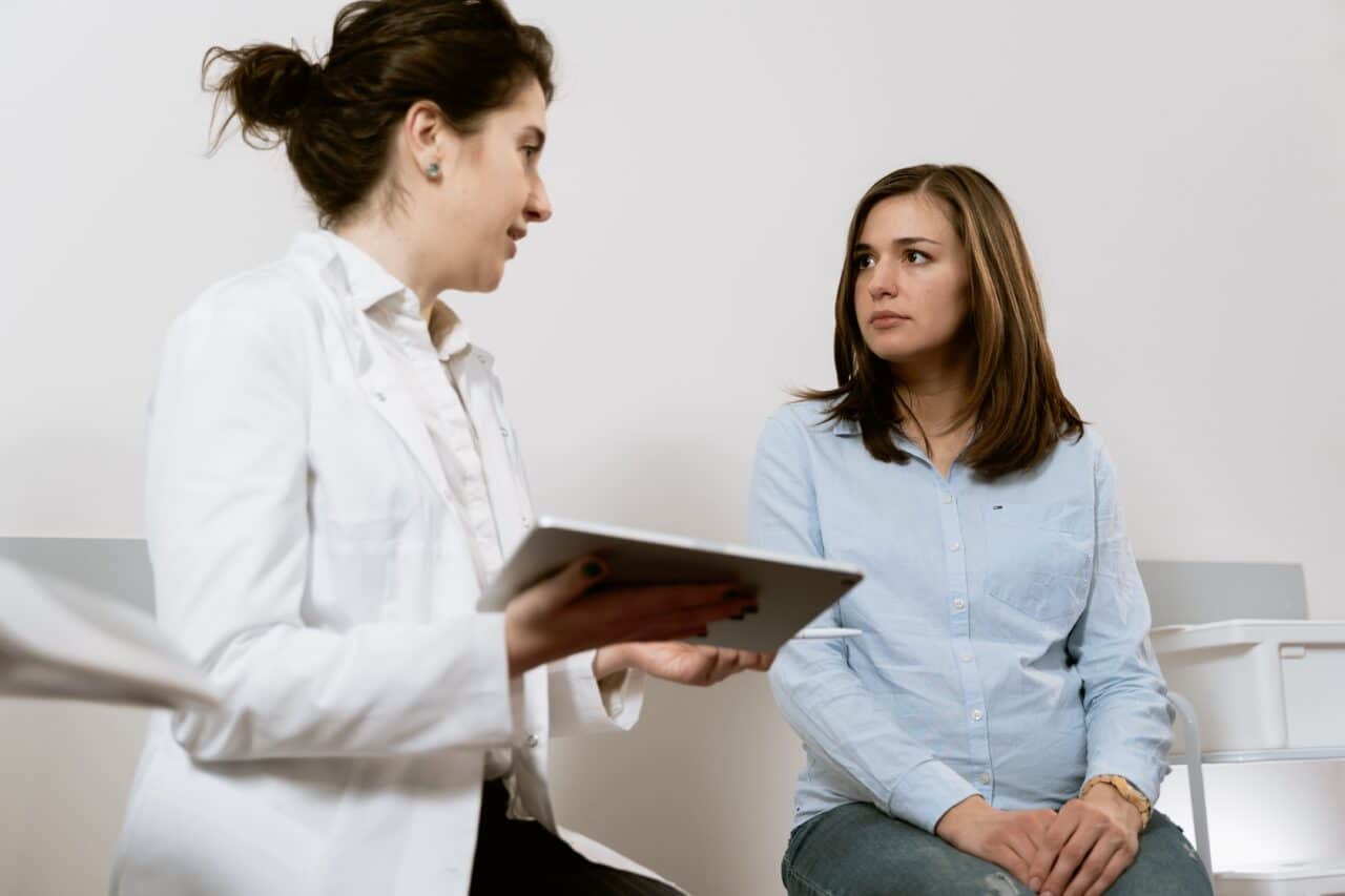 Woman talking with her allergist in exam room.