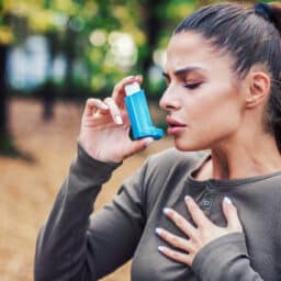 Young woman using an inhaler to treat asthma symptoms.