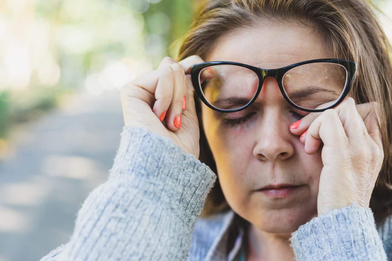 Woman rubbing her eye outdoors.