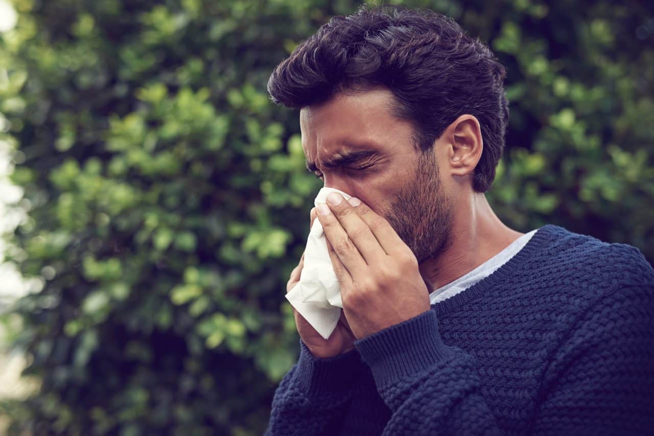 a man blows his nose while outdoors