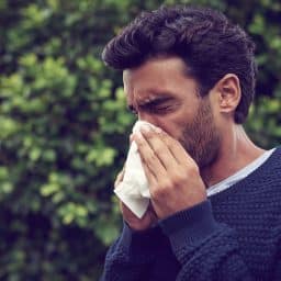 a man blows his nose outdoors
