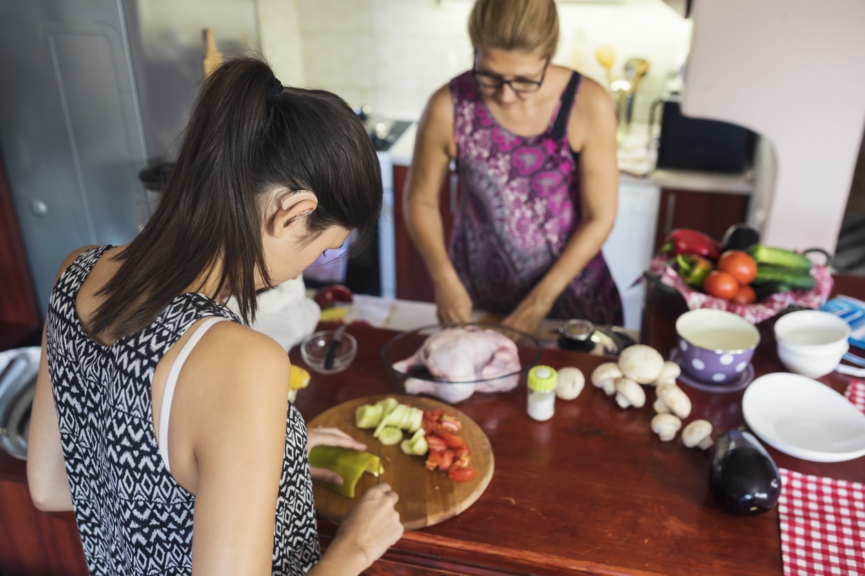 Woman wearing hearing aids making dinner with her mom