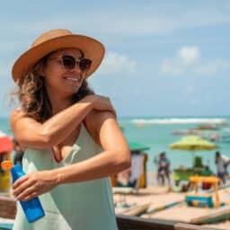 Woman at the beach putting on sunscreen