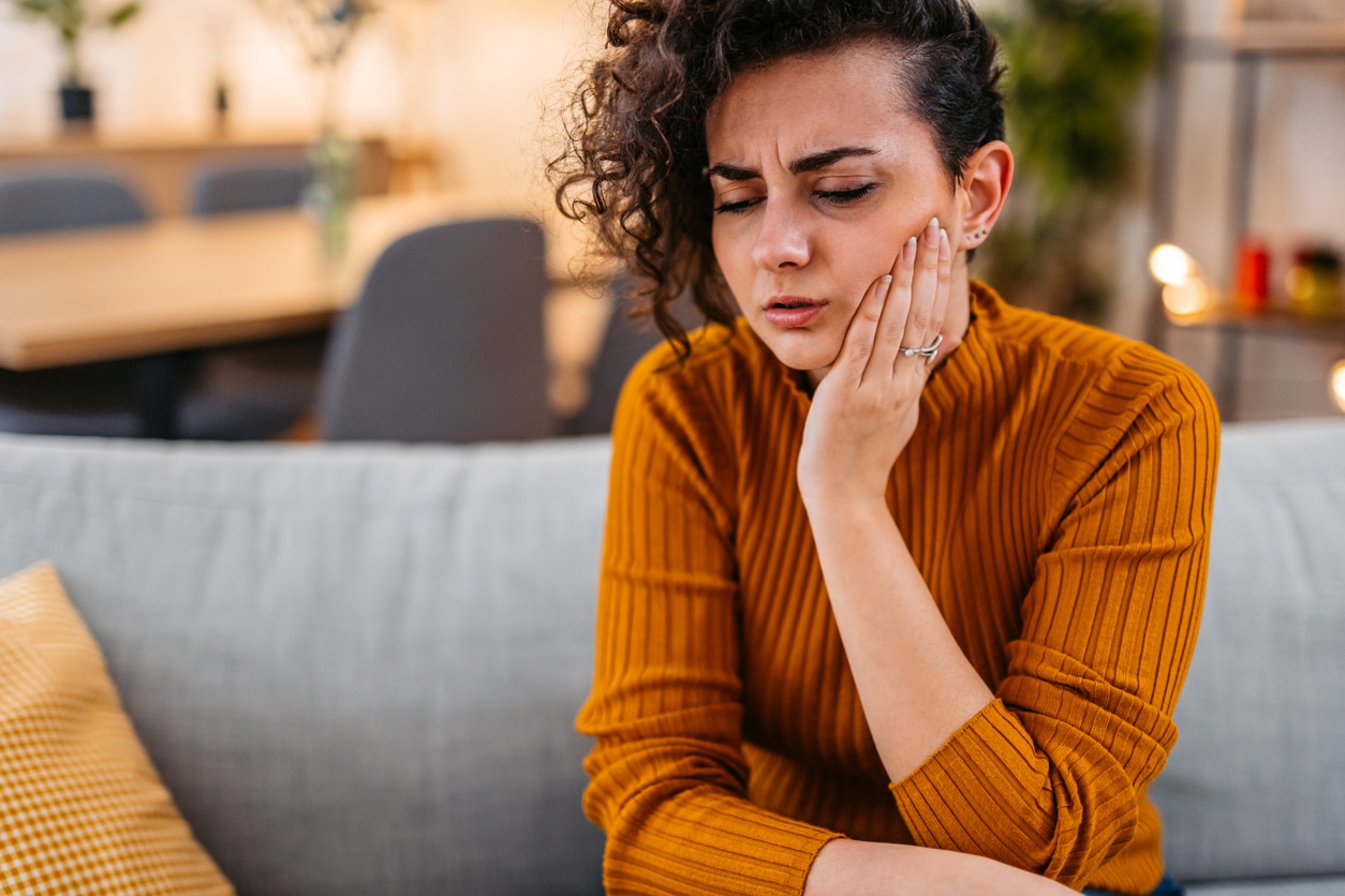 Woman experiencing toothache holding her jaw.