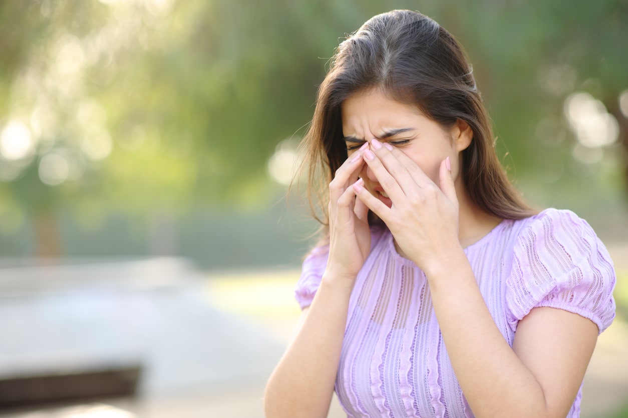 Woman rubbing her sinuses in the park.