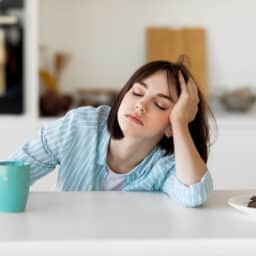 Tired woman leaning on counter, holding mug