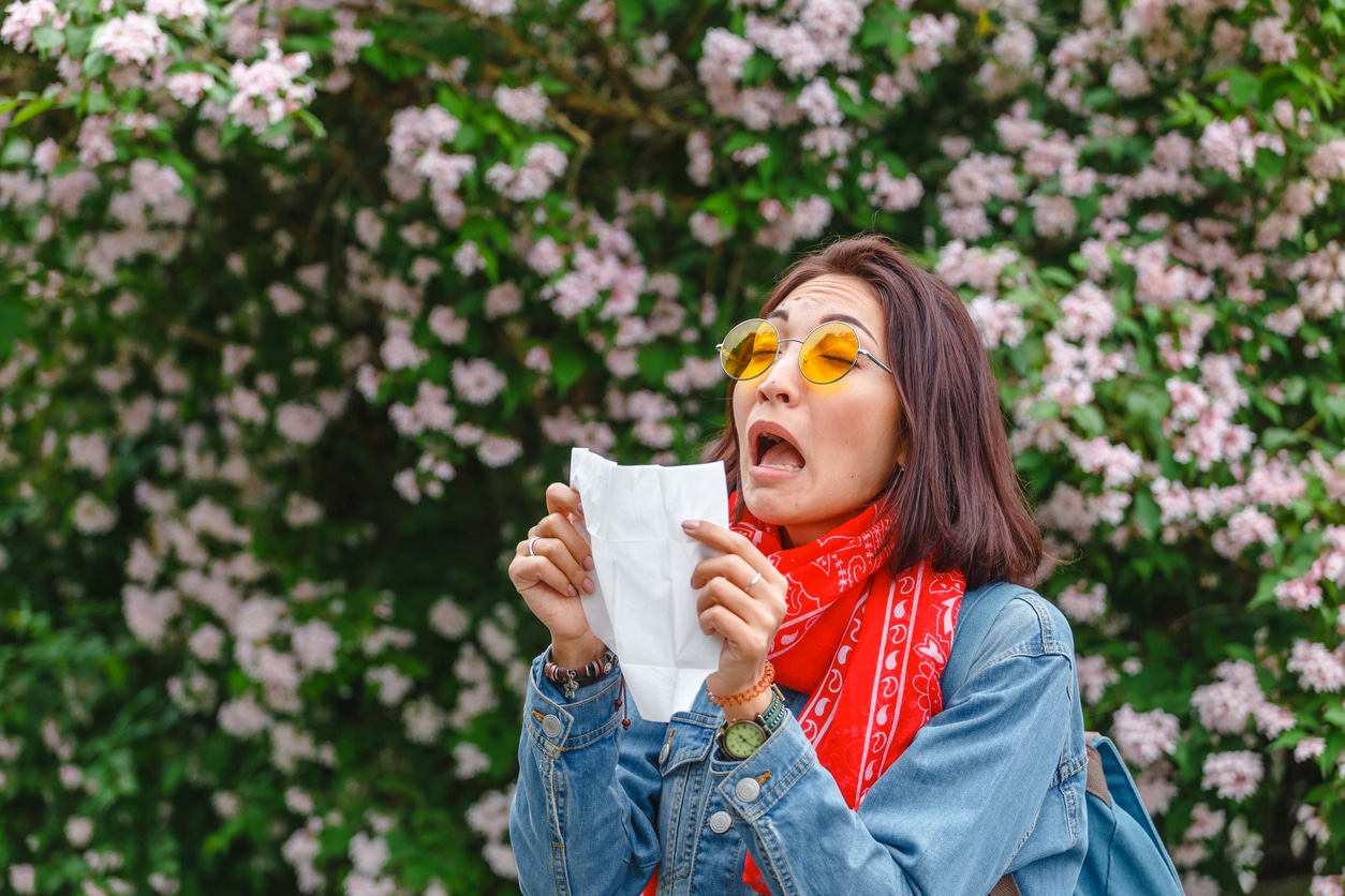 Woman about to sneeze into a napkin in the park.