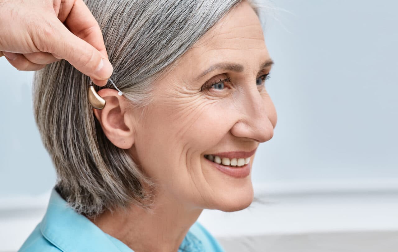 Hearing aid is placed behind woman's ear 