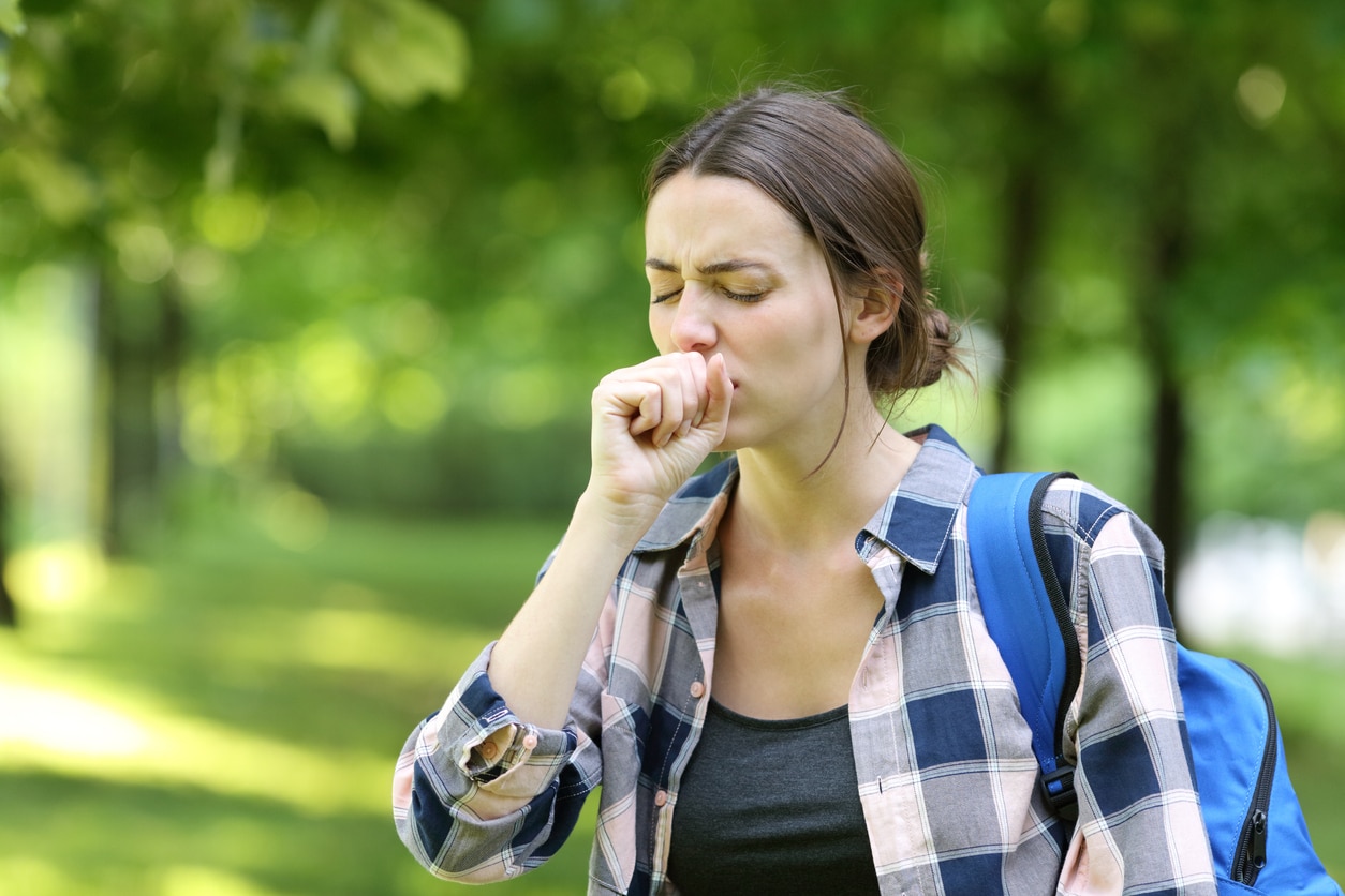 Woman coughs outside in a park