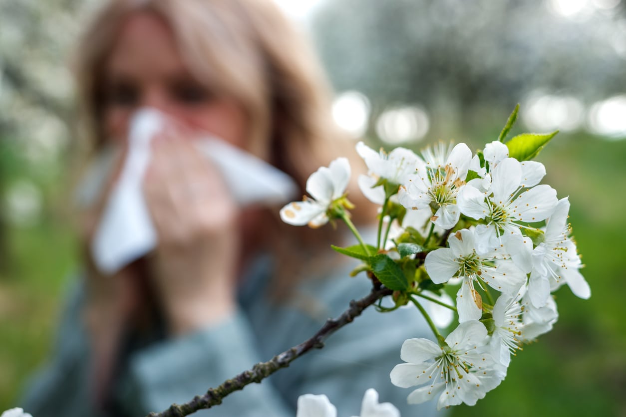 Woman blows nose by flower