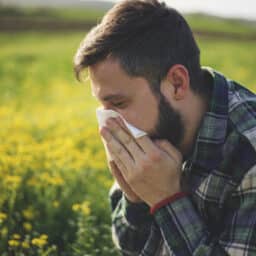 Man blows nose in field