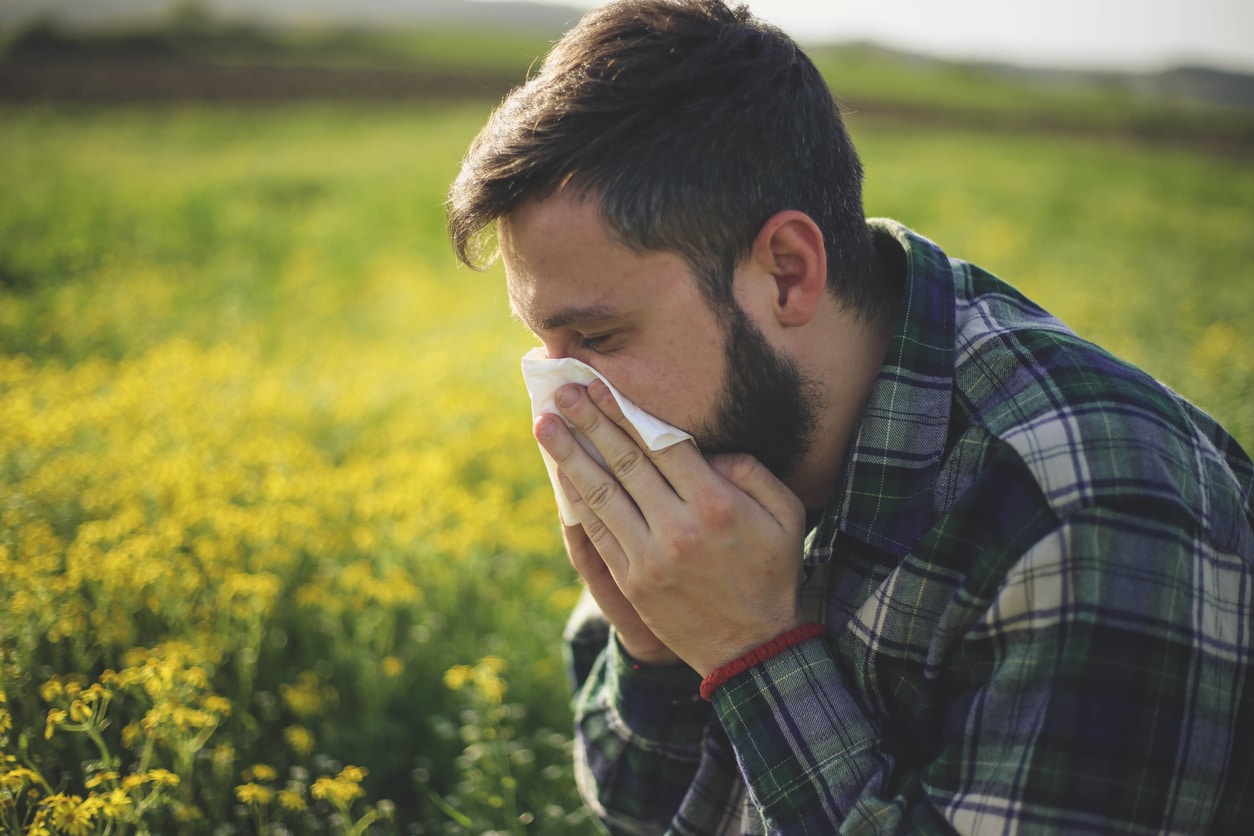 Man blows nose in field