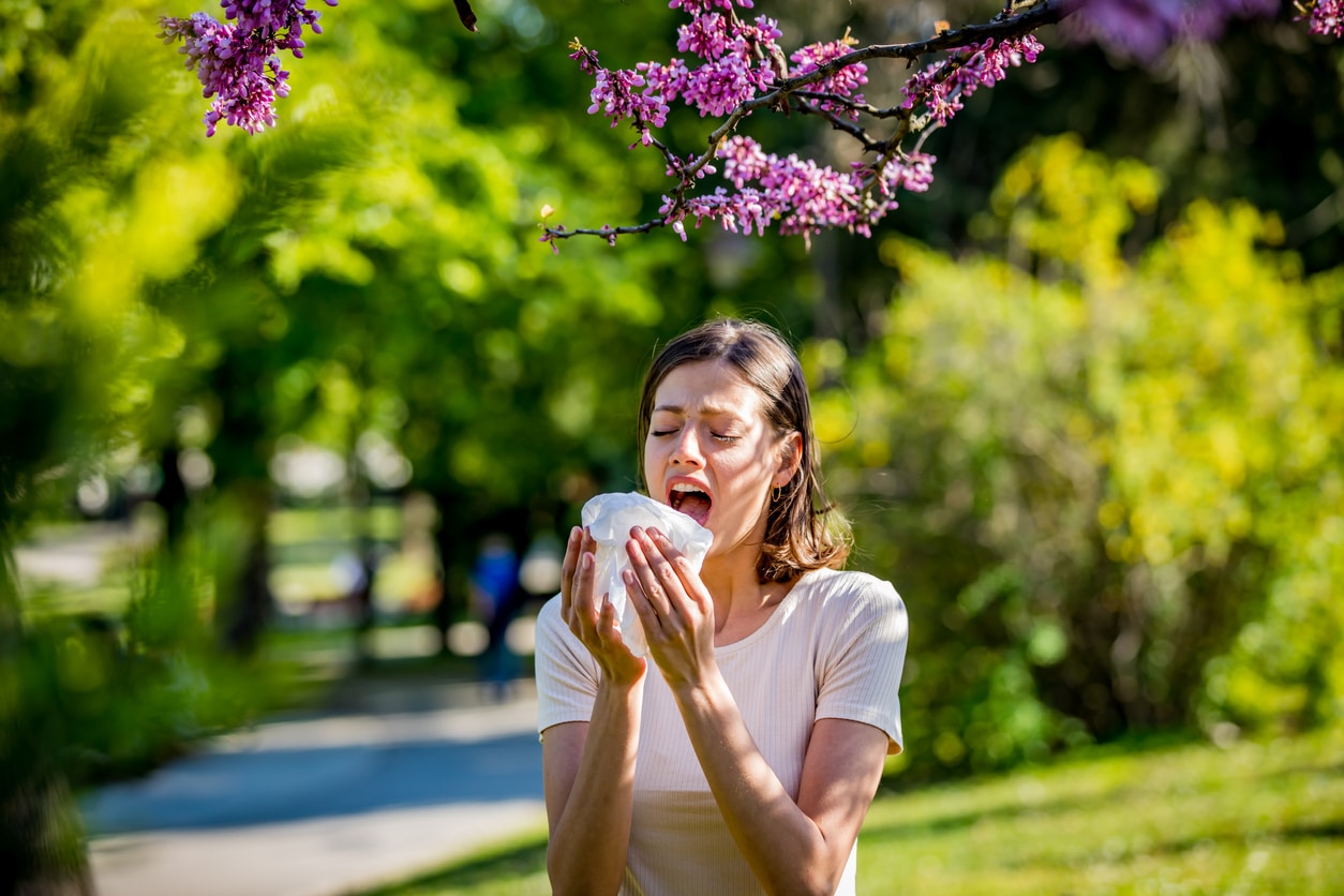 Woman sneezes near trees