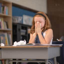 Young girl blows nose in classroom
