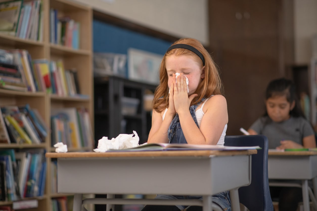 Young girl blows nose in classroom