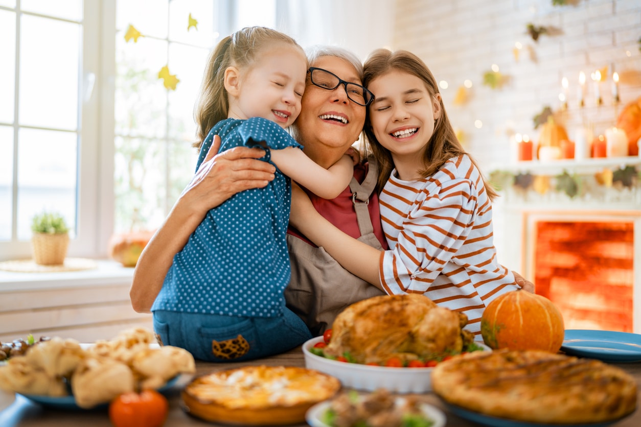 Happy grandma hugging her granddaughters on Thanksgiving.