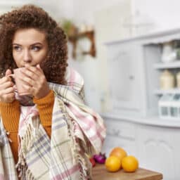 Woman with a cold drinking a hot cup of tea