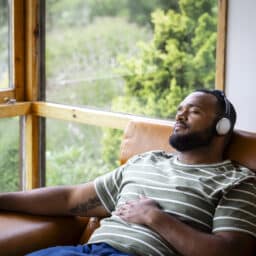 Man on a couch listening to music through her headphones