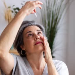 Senior woman applying eye drops suffering from allergies