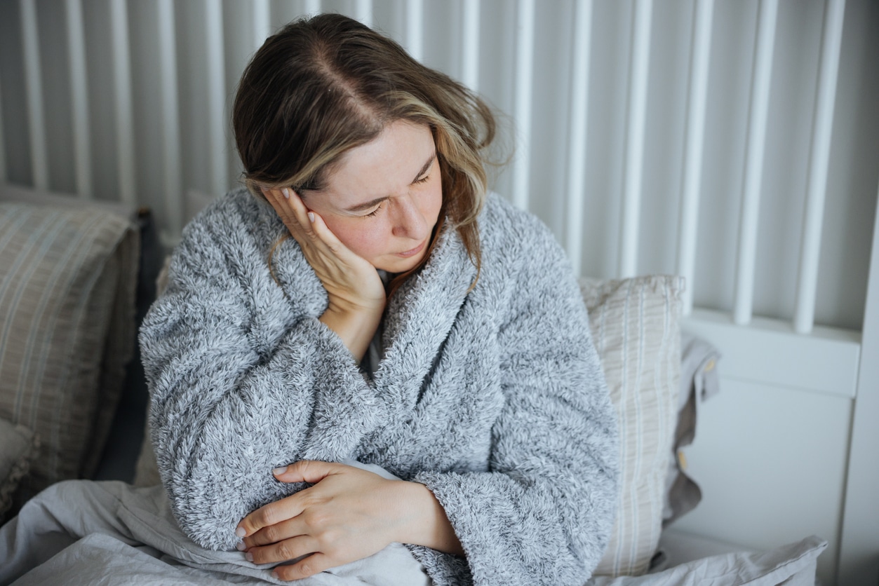 Woman holds ear in pain 