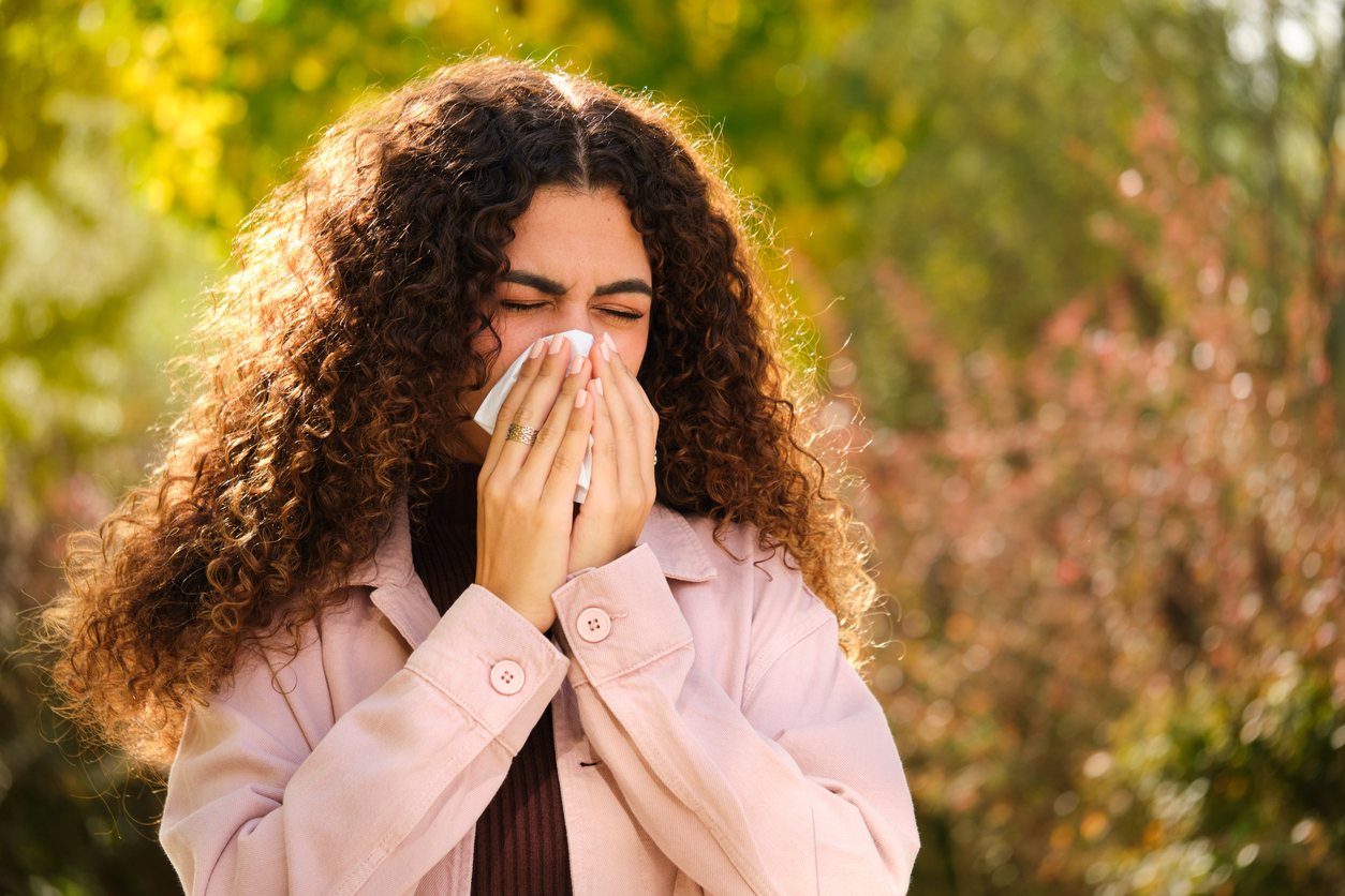 Woman sneezes in park